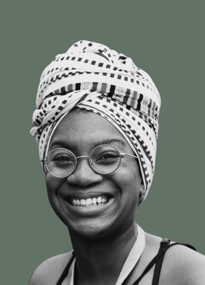 Woman with a headwrap and glasses with a joyful smile. The image has a monochrome filter with a green background.