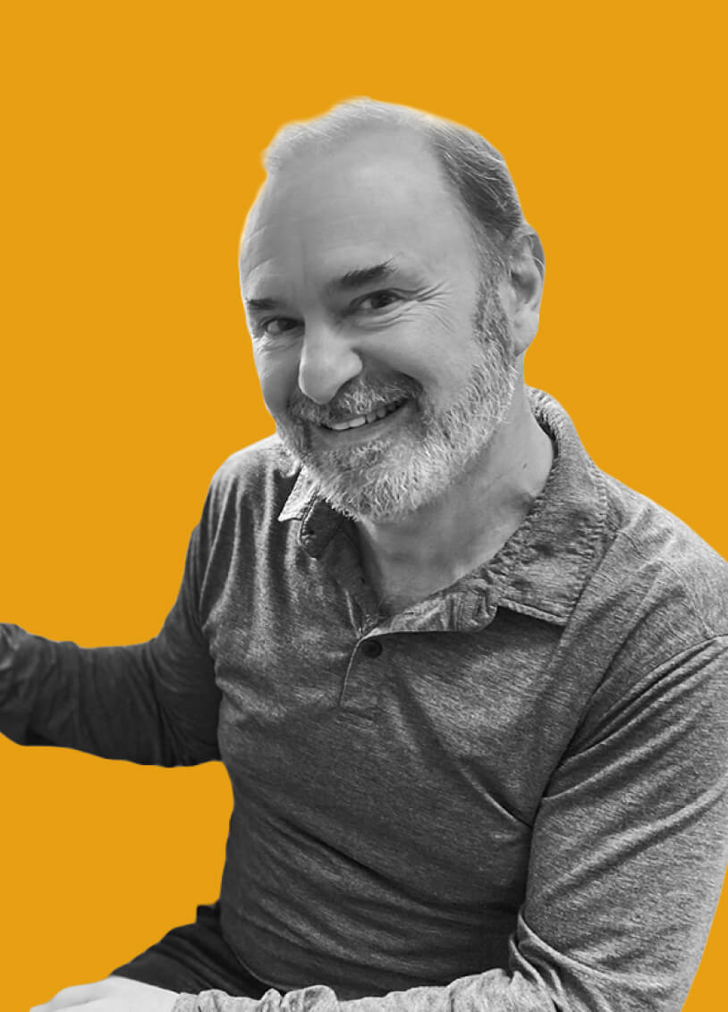 Bearded man wearing a gray popover shirt looking directly at the camera and smiling. The image has a monochrome filter with an orange background.