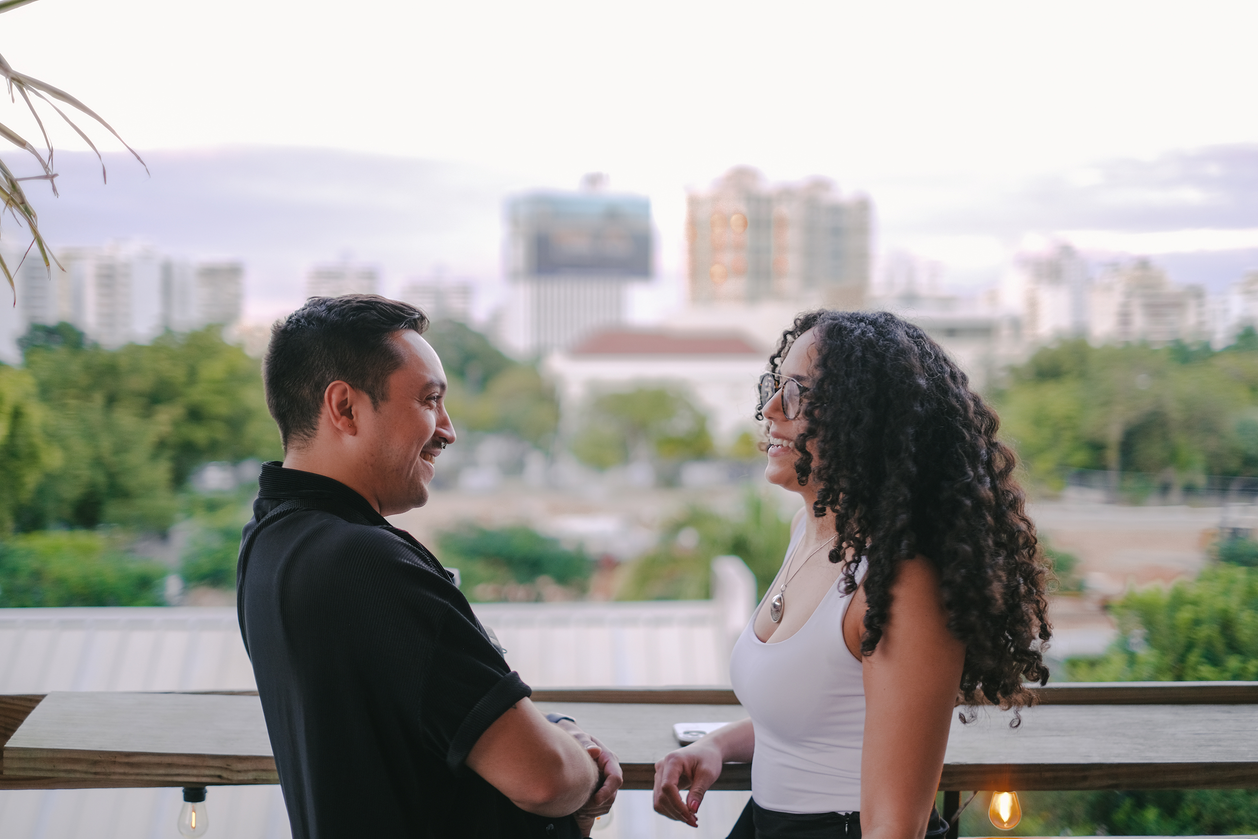 Candid photo of Salem Acuna-Vasquez & Claribel Vidal laughing together with Puerto Rico’s skyline in the background